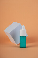 Green glass cosmetic bottle, Skin care or sunscreen cosmetic with stylish props on cream background.