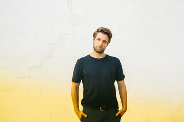 Portrait of a man standing casually with his hands in his pockets, wearing a dark shirt and jeans,...