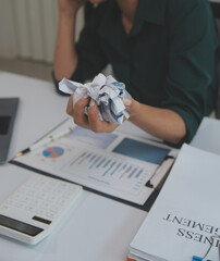 Fototapeta premium Asian women sitting in a home office With stress and eye strain.Tired businesswoman holding eyeglasses and massaging nose bridge. There are tablets, laptops, and coffee.