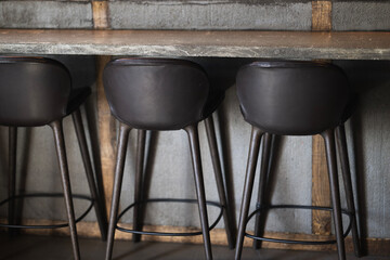 Chairs in a modern bar or on a modern breakfast counter made from concrete and wooden planks,...