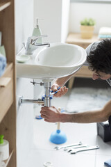 Professional plumber checking a sink drain