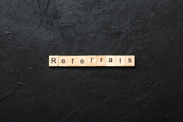 REFERRALS word written on wood block. REFERRALS text on cement table for your desing, concept