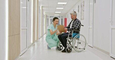 A middle-aged man in a wheelchair talks with a nurse in a hospital corridor, reflecting care and support. Middle-Aged Man in Wheelchair with Nurse in Hospital Corridor. - Powered by Adobe