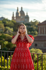 Fototapeta premium Young 20s blond girl walking with city landscape on background. Tourist enjoying sightseeing of Montjuic Park in Barcelona, Spain.