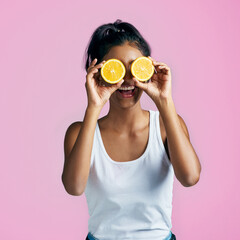 Girl, portrait and funny with orange slices as gen z on pink background for fashion, style and energy. Female person, happiness and fruit in playful, aesthetic or creativity in studio backdrop