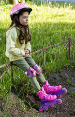 Little pretty girl on roller skates in helmet at a park. Cheerful preschool girl wearing inline...