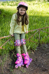 Little pretty girl on roller skates in helmet at a park. Cheerful preschool girl wearing inline...
