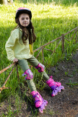 Little pretty girl on roller skates in helmet at a park. Cheerful preschool girl wearing inline...