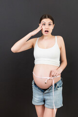 pregnant woman using tape measure to check baby development and the growth of belly. Inch...