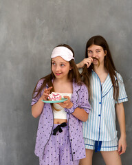 Girls in pajamas eating dessert and making funny faces.