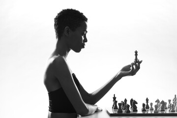 Attractive woman playing chess and holding the queen