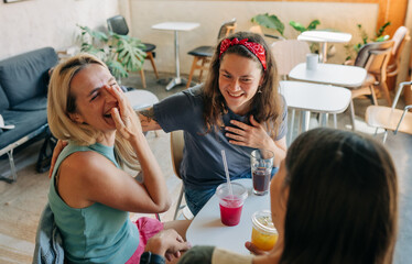 Cheerful happy laughing women sitting in a cafe at a meeting communicate and celebrate.