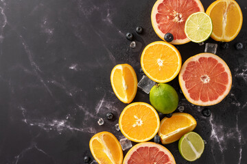 Freshly sliced citrus fruits including oranges, grapefruits, and limes on a dark marble background....