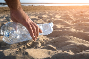 Hand picking up plastic bottle cleaning on the beach , volunteer concept