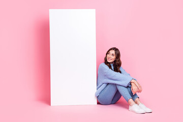 Full body photo of cheerful lady sit floor look huge empty space banner isolated on pink color background