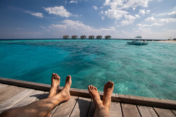 beach holidays in Maldives for couple, summer vacation travel, feet of man and woman sitting near...