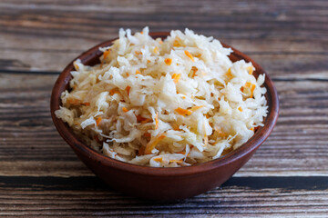 Homemade fermented cabbage with carrot Sauerkraut in bowl on wooden background.