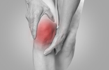 Fototapeta premium Elderly woman holding her knees with her hands due to pain due to degenerative arthritis on an isolated background