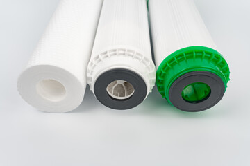 Set three of cartridges for water filter with clear glass of water. Concept of water treatment technology. filter cartridges to domestic water treatment systems.	
