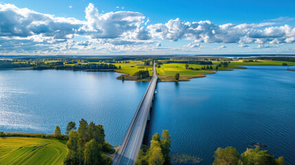 Drone shot of a scenic bridge over a blue lake, bordered by green and yellow farmlands under a...
