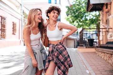 Two young beautiful smiling hipster female in trendy summer white t-shirt and shorts clothes. Sexy...