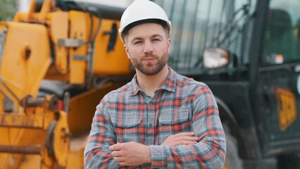 In white hard hat. Man is with tractor. Agricultural worker.