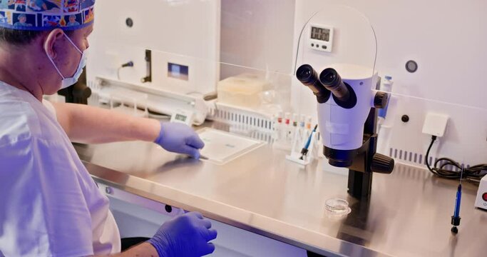 An embryologist conducts an in vitro fertilization IVF procedure in a laboratory, using a microscope and specialized tools to fertilize a human egg. Embryologist Conducting Artificial Fertilization