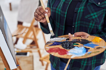 Fototapeta premium Person, hands and art palette in closeup with easel and canvas for creative expression and hobby. Painter, artwork and color mixing tool with brush and sustainable materials for watercolor project