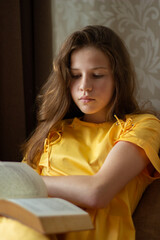 Fototapeta premium Romantic photo, girl with long hair in a dress reading a book, teenagers reading 