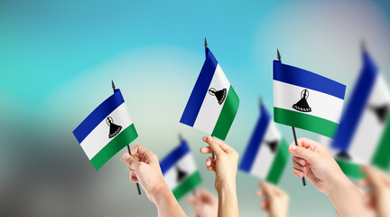 A group of people are holding small flags of Lesotho in their hands.