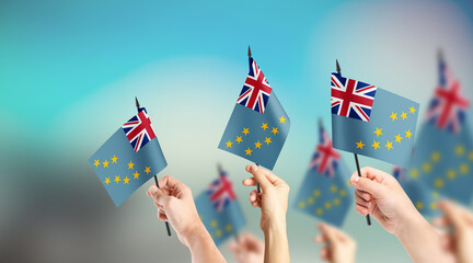 A group of people are holding small flags of Tuvalu in their hands.