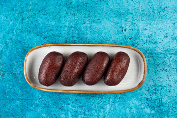 Gulab Jamun, kalo jam or mohan served in tray dish isolated on blue background top view of indian,...