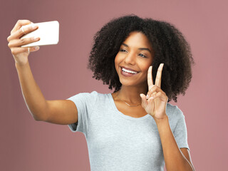 Peace sign, selfie and social media with afro black woman in studio on pink background for profile...