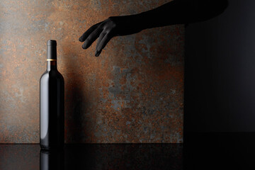 Woman hand in  glove reaches for a bottle of red wine.