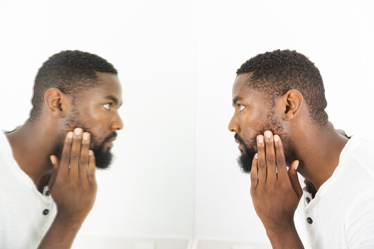 At home in bathroom, African American man touching chin, examining face