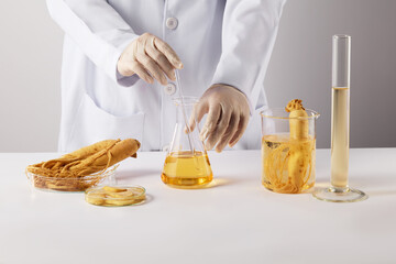 Front view photo on white texture, a researcher holds a glass stick stirring yellow solution in...