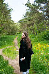 Woman walking in the park at springtime in black coat. High quality photo