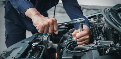 Mechanic using wrench while working on car engine outside the service center , Repair and service.