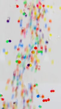 Multicolored orbis is poured and floats in clear water. Kurny plan. Colorful, small balls fall into the water. and