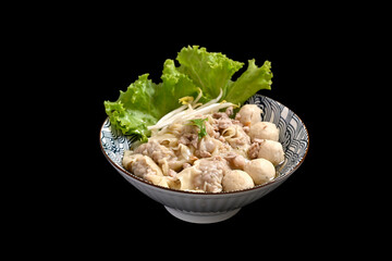 Bowl of delicious pork dumplings soup with meatballs and vegetables isolate black background