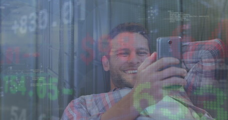 Image of stock market data processing over caucasian man smiling while using smartphone