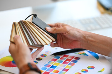 Close up hands of Interior designer choosing laminate floor samples at desk. Home design and...