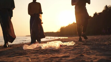 Earth day. Volunteers activists collects garbage cleaning of beach coastal zone. Woman and mans puts plastic trash in garbage bag on ocean shore. Environmental conservation coastal zone cleaning