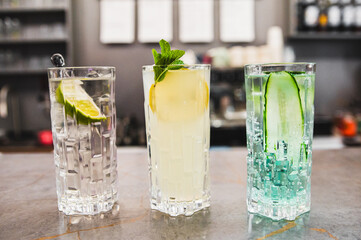 Three refreshing cocktails with garnishes on a bar counter, showcasing variety and mixology appeal