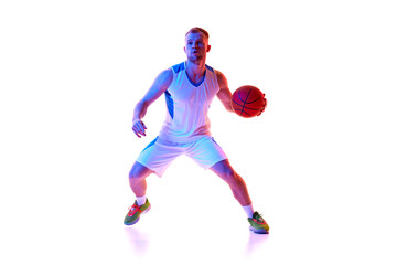 Young athletic man, professional basketball player dressed red uniform ready to score goal in neon light against white background. Concept of professional sport, games, tournament, action. Ad