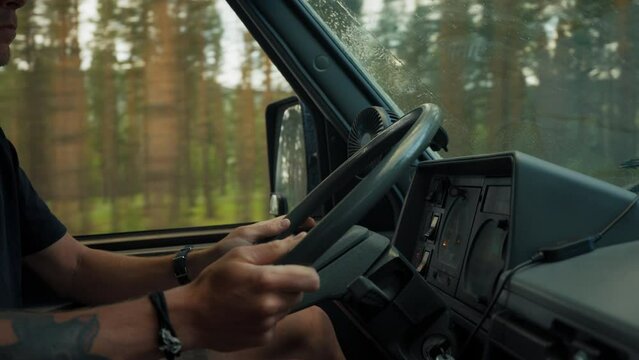 Side shot of travel vlogger and adventurer drive cool old camping van with old school dashboard and steering wheel. Traveller drive on forest road in rain. Camper vanlife adventures and roadtrip