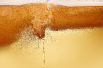 Macro shot of beer tap pouring golden beer into tilted glass. Glass perspiring with condensation....