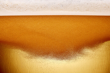 Close-up shot of beer tap pouring frothy beer into clear glass. Beer light-colored and bubbly. Textured photo. Abstract background. Concept of alcohol drinks, Oktoberfest, summer, party.