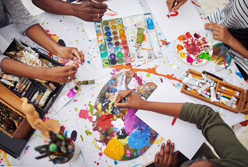 Hands, palette and paintbrush for art, above and collaboration for painting, craft and tools for color. Workshop, equipment and supplies for canvas, hobby and group of creative people in studio