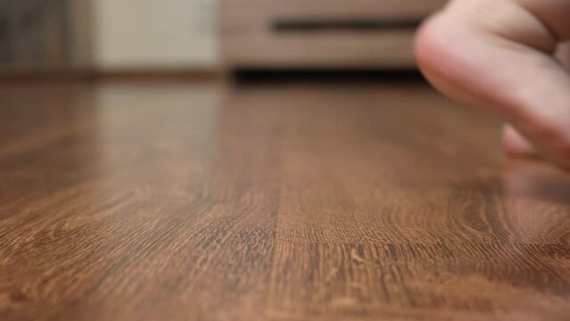 The baby's bare feet stomp on the parquet floor. Shooting from the side. Close-up. Slow motion. An unrecognizable baby walks barefoot on a wooden parquet floor. 4k footage